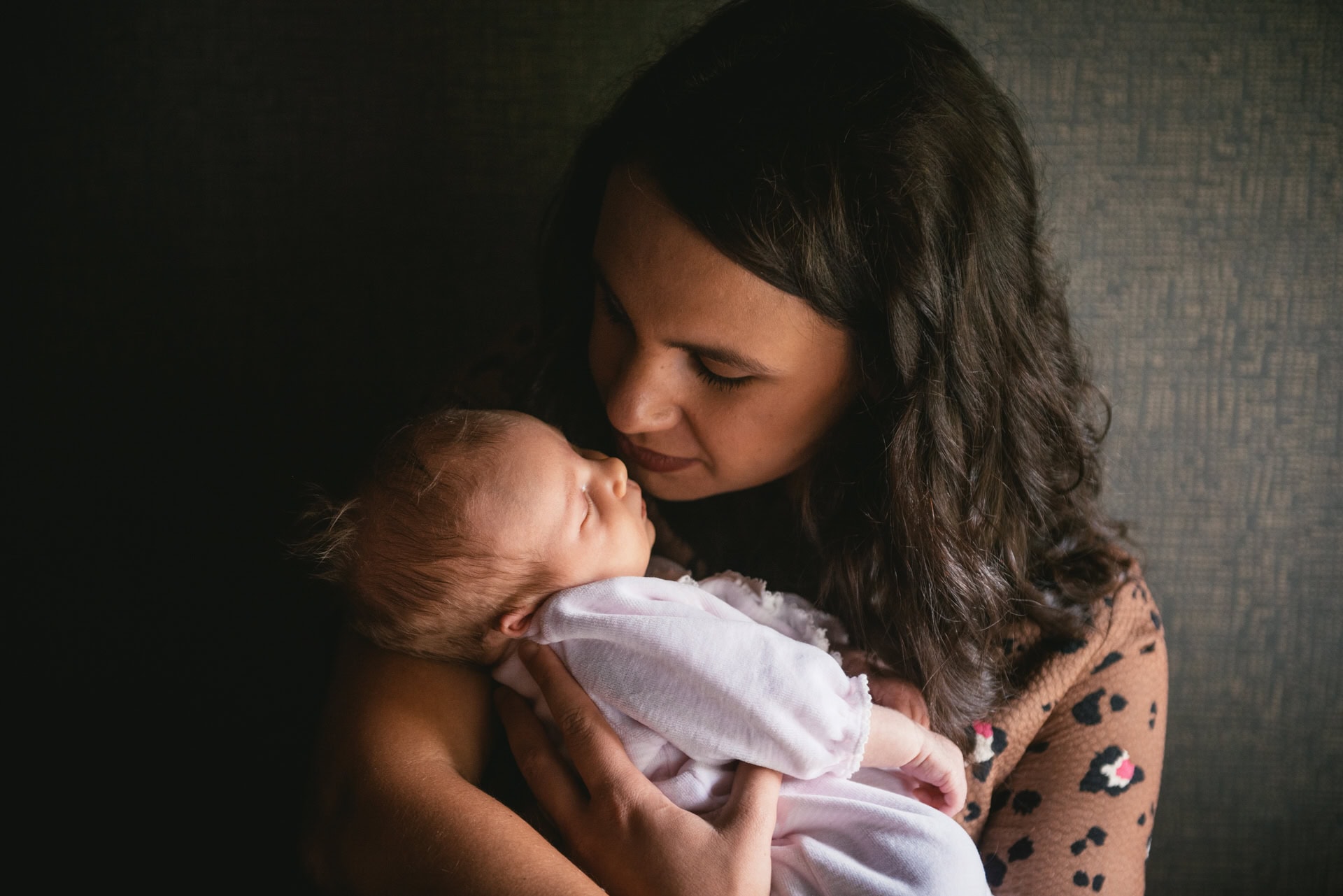 Les mains des parents autour d'un nouveau-né, séance naissance en extérieur